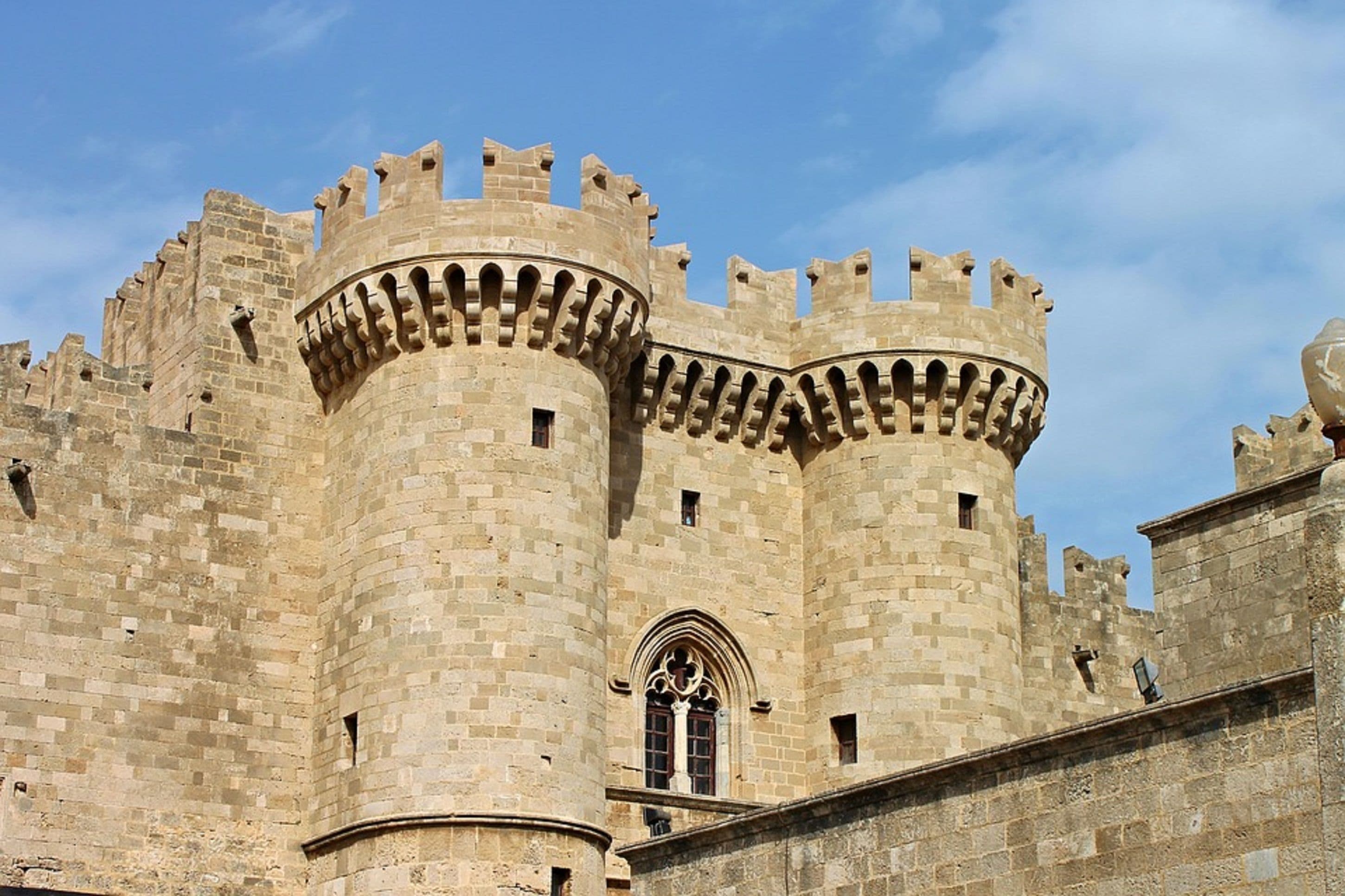 A historic stone castle with two prominent towers, arched windows, and a crenellated parapet.