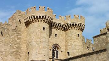 A historic stone castle with two prominent towers, arched windows, and a crenellated parapet.