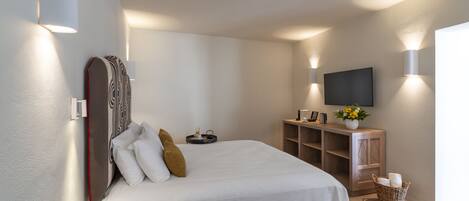 A modern bedroom with a large bed, wall-mounted TV, and ambient lighting.