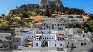 A coastal town with white buildings, a castle on a hill, and a clear blue sky. - Maris Lindos, Suites and Apartments (Rhodes)