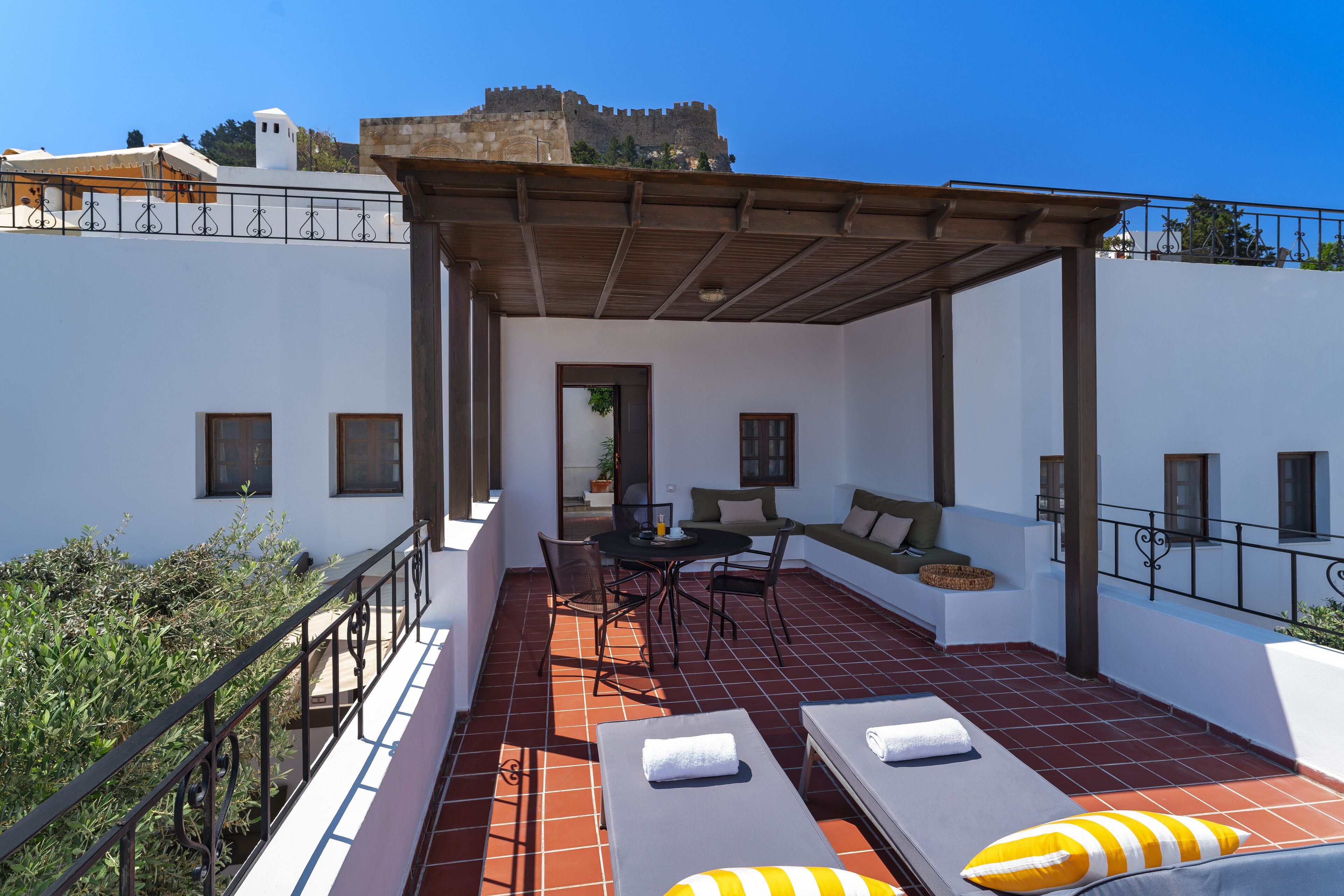 Eine Dachterrasse mit einer Pergola, Lounge-Stühlen, einem Tisch und Sesseln.