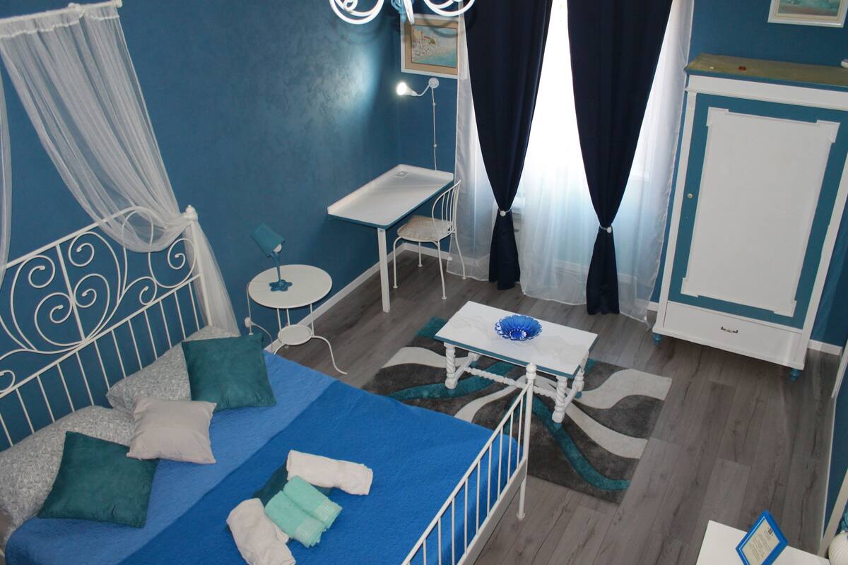 A room with a bed, a small table, a chair, a desk, and a cabinet.