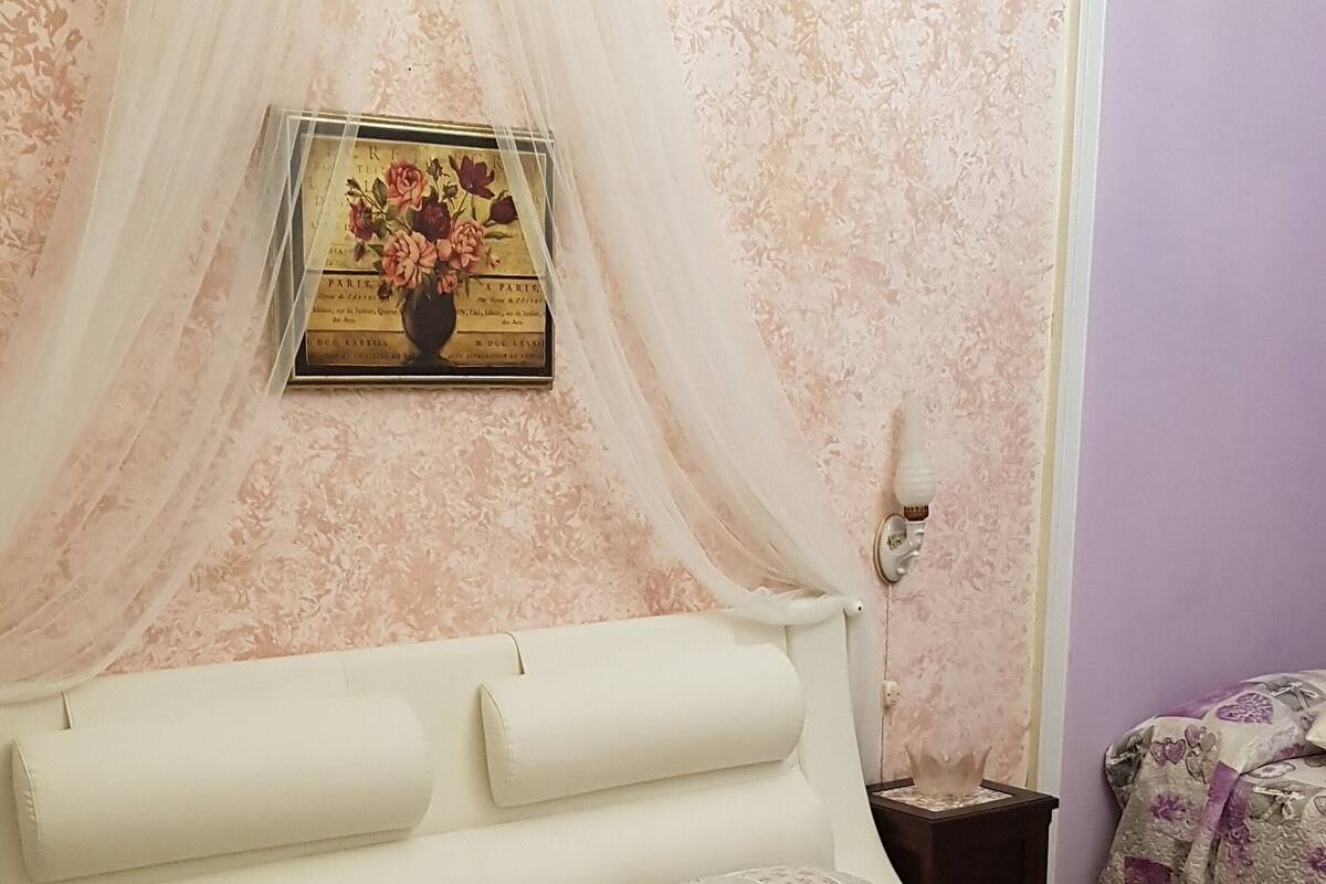 A bedroom with a bed, a nightstand, a lamp, and a framed picture on the wall.