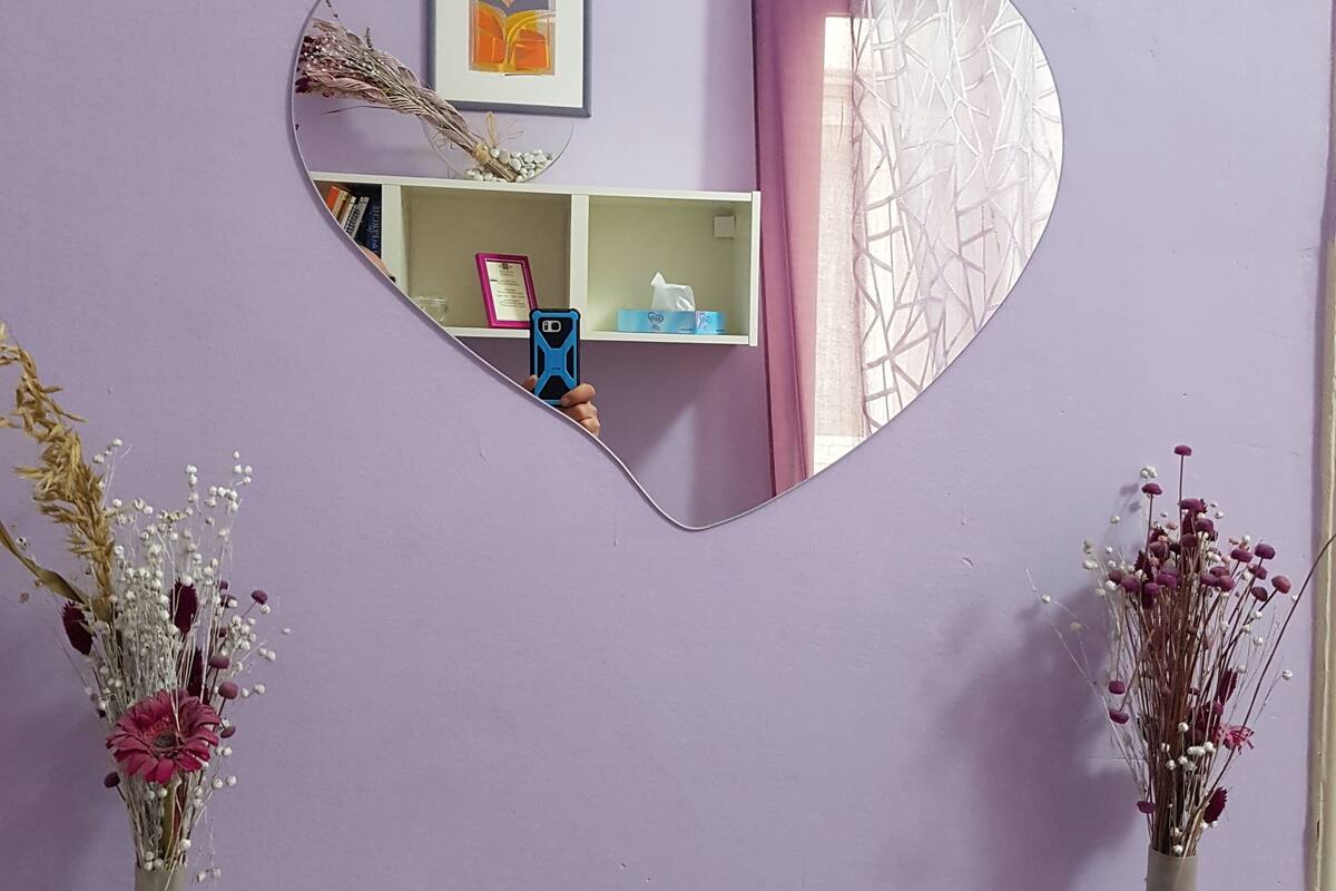 A heart-shaped mirror on a wall with a purple background.