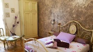 A bedroom with a bed, a nightstand, a chair, a table, and a wardrobe. - Bed and Breakfast Al Cucherle (Trieste)