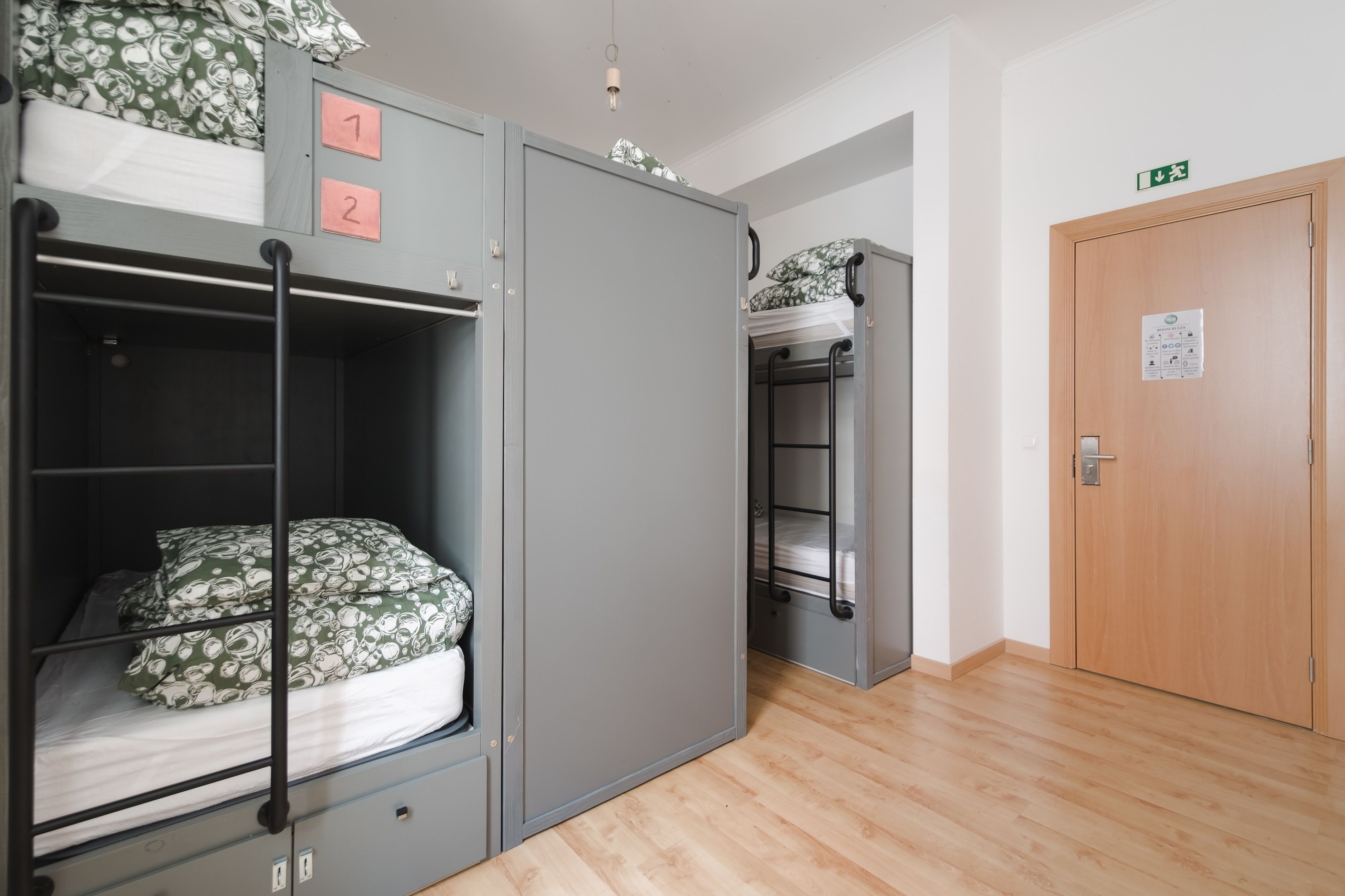 Une chambre de dortoir avec des lits superposés, une armoire et une porte en bois.