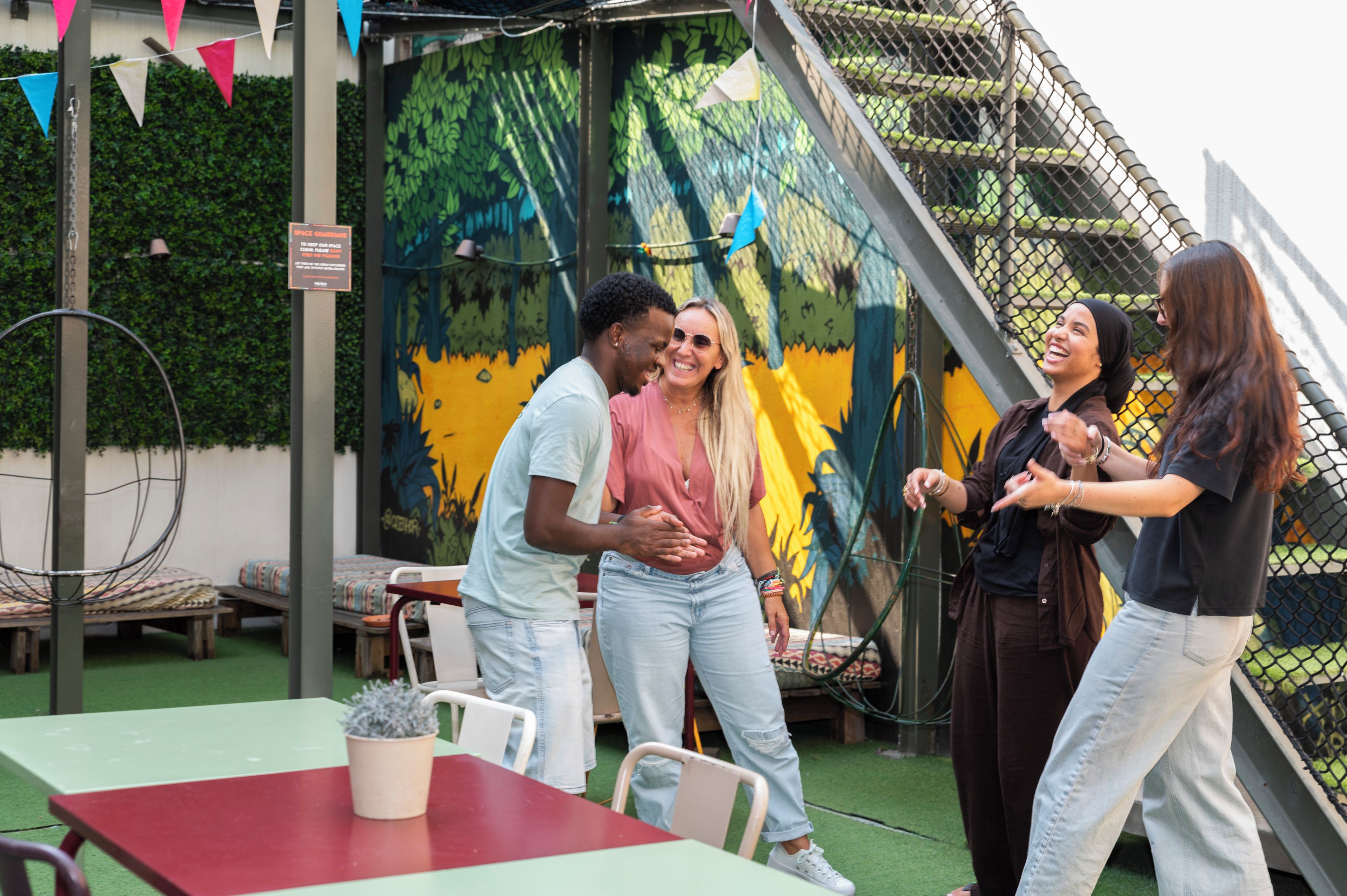 A group of people standing around a table with a mural in the background.