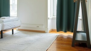 Ein Zimmer mit einem Bett, einem Staffelei, einer Whiteboard-Tafel und einem Fenster mit Vorhängen.