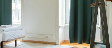A room with a bed, a standing easel, a whiteboard, and a window with curtains.