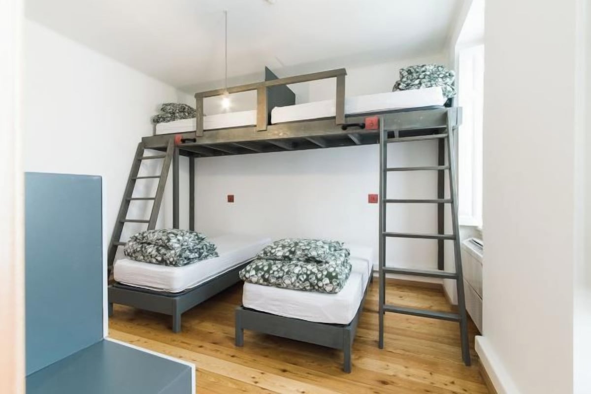 Habitación con literas, dos camas, cada una con almohada y manta. Hay dos escaleras, una a cada lado de las camas.