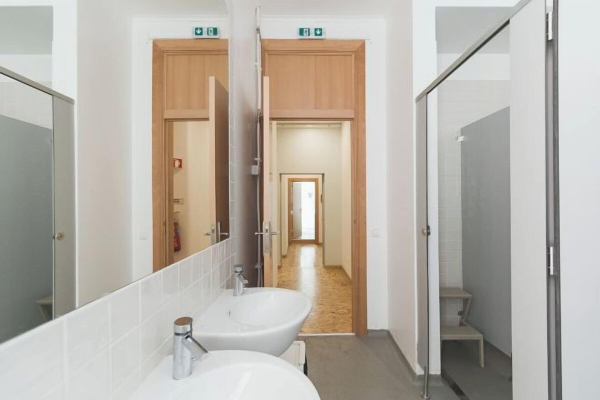 Un baño moderno con un espejo grande, dos lavamanos y una zona de ducha.