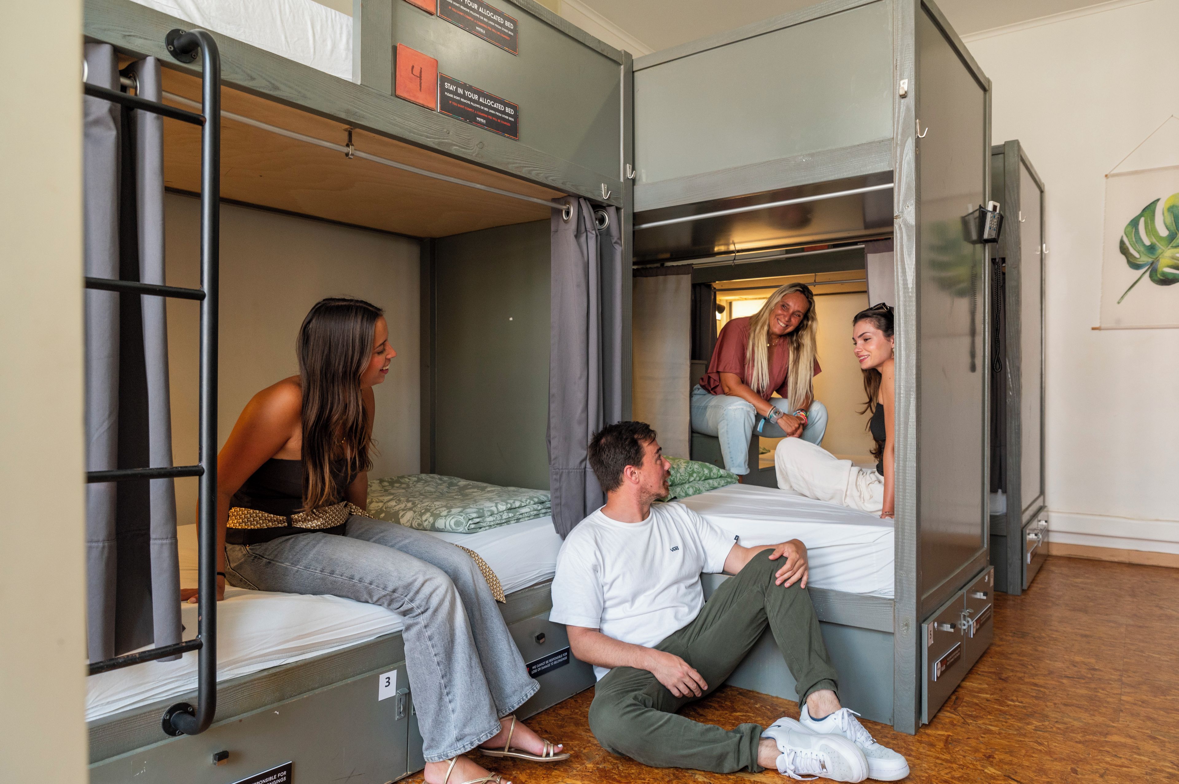 A dormitory room with bunk beds, a small table, and a wall-mounted telephone.