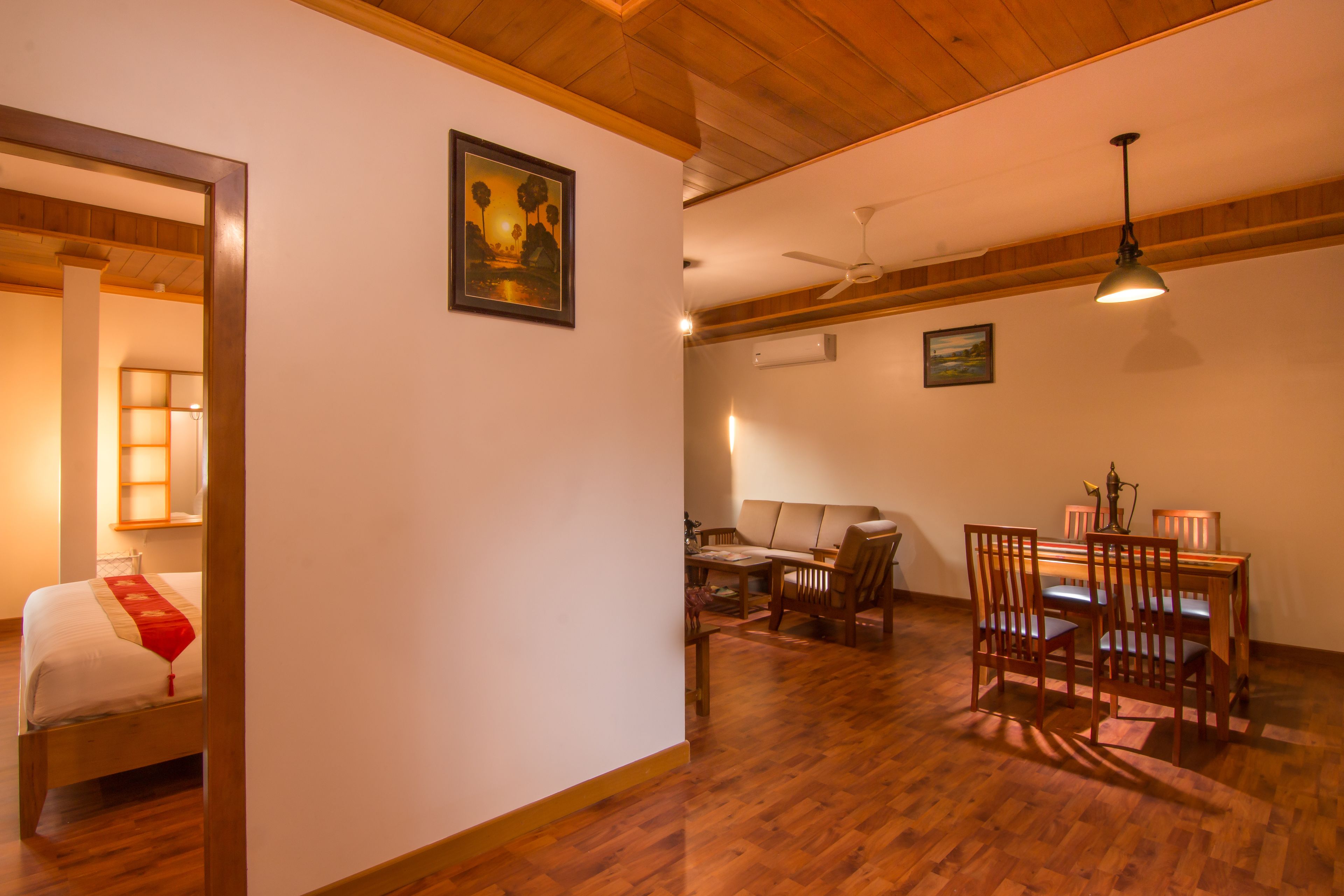Una habitación con cama, una mesa de comedor con sillas, un ventilador de techo y una lámpara de pared.