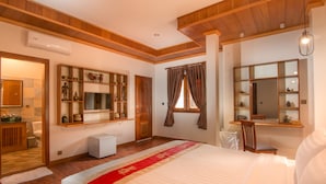 A hotel room with a large bed, wooden ceiling, built-in shelves with decorative items, a small desk, and a window with curtains. - BB Angkor Residence (Siem Reap)