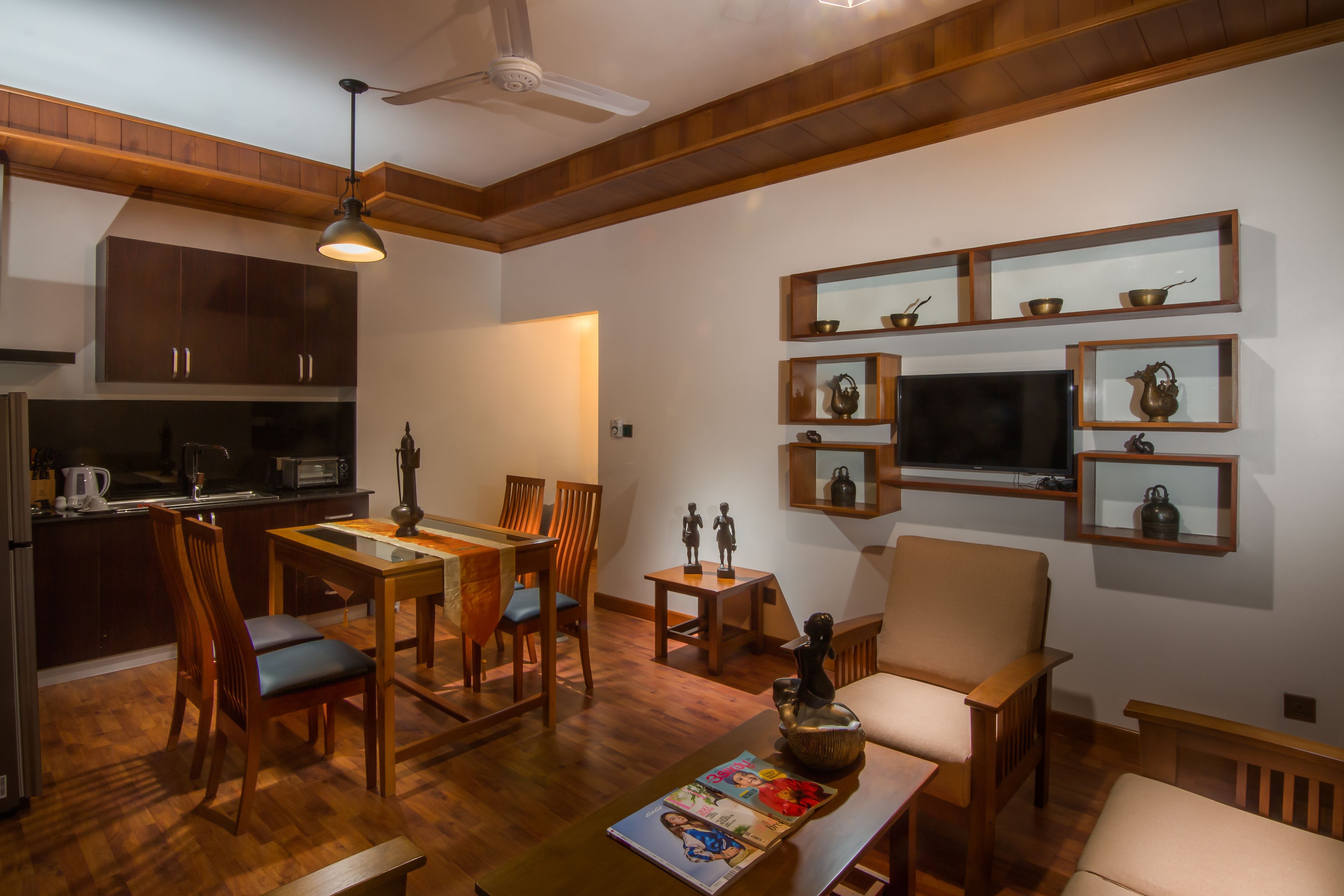 A modern living room with wooden furniture, a dining area, and a kitchen in the background.
