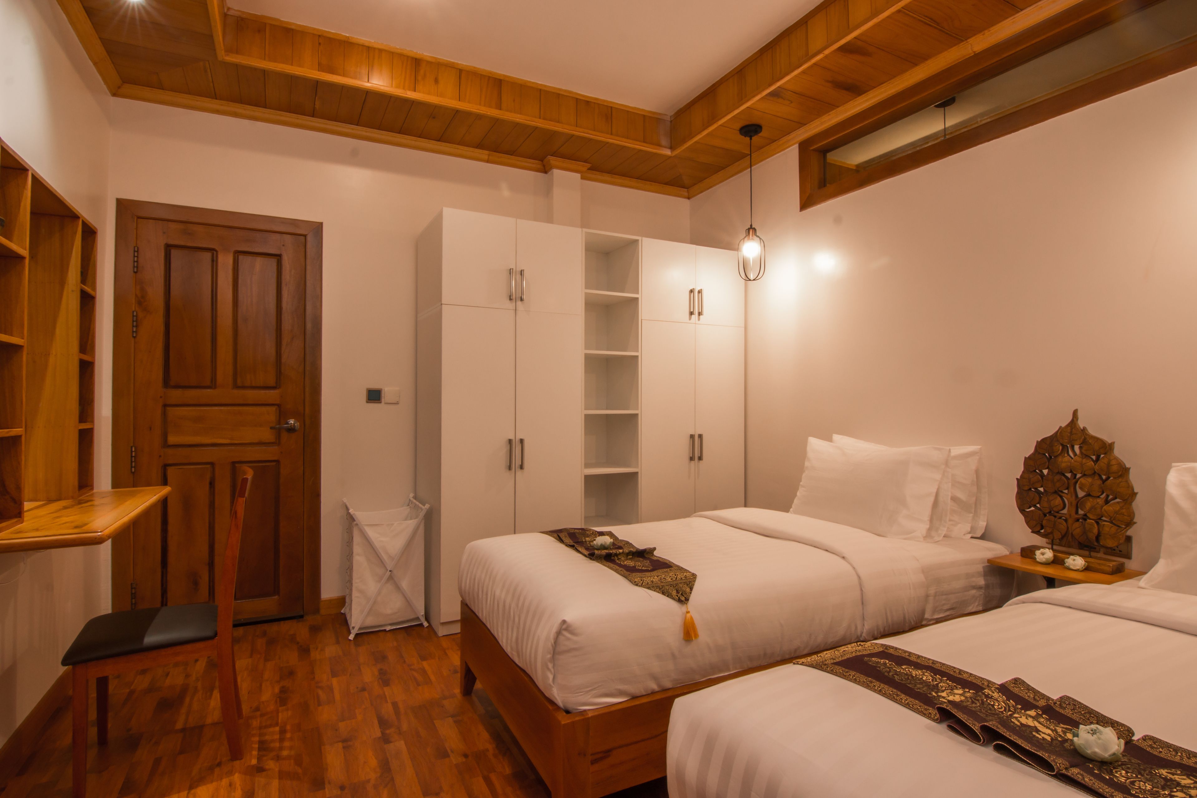 Een slaapkamer met twee bedden, houten meubels en inbouwplanken.