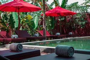 A poolside area with red umbrellas, lounge chairs, and rolled towels. - BB Angkor Residence (Siem Reap)