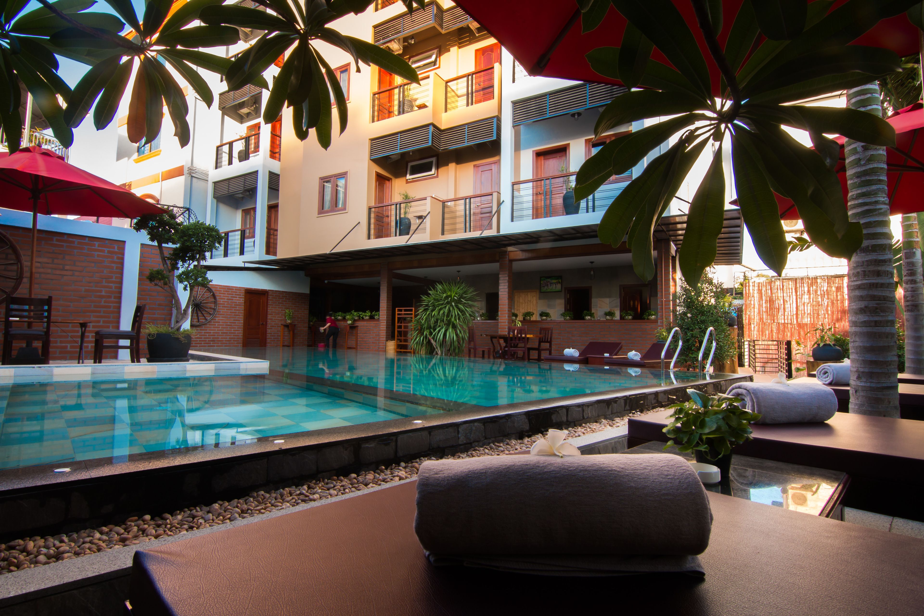 A hotel pool area with a clear pool, lounge chairs, and umbrellas.
