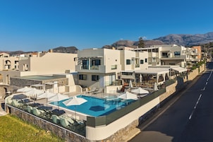 Un hotel moderno con piscina en la azotea, zona de estar al aire libre y vistas a la montaña.