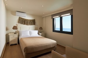 Un dormitorio con cama, mesitas de noche, lámparas, aire acondicionado, ventana con vistas e iluminación empotrada en el techo.