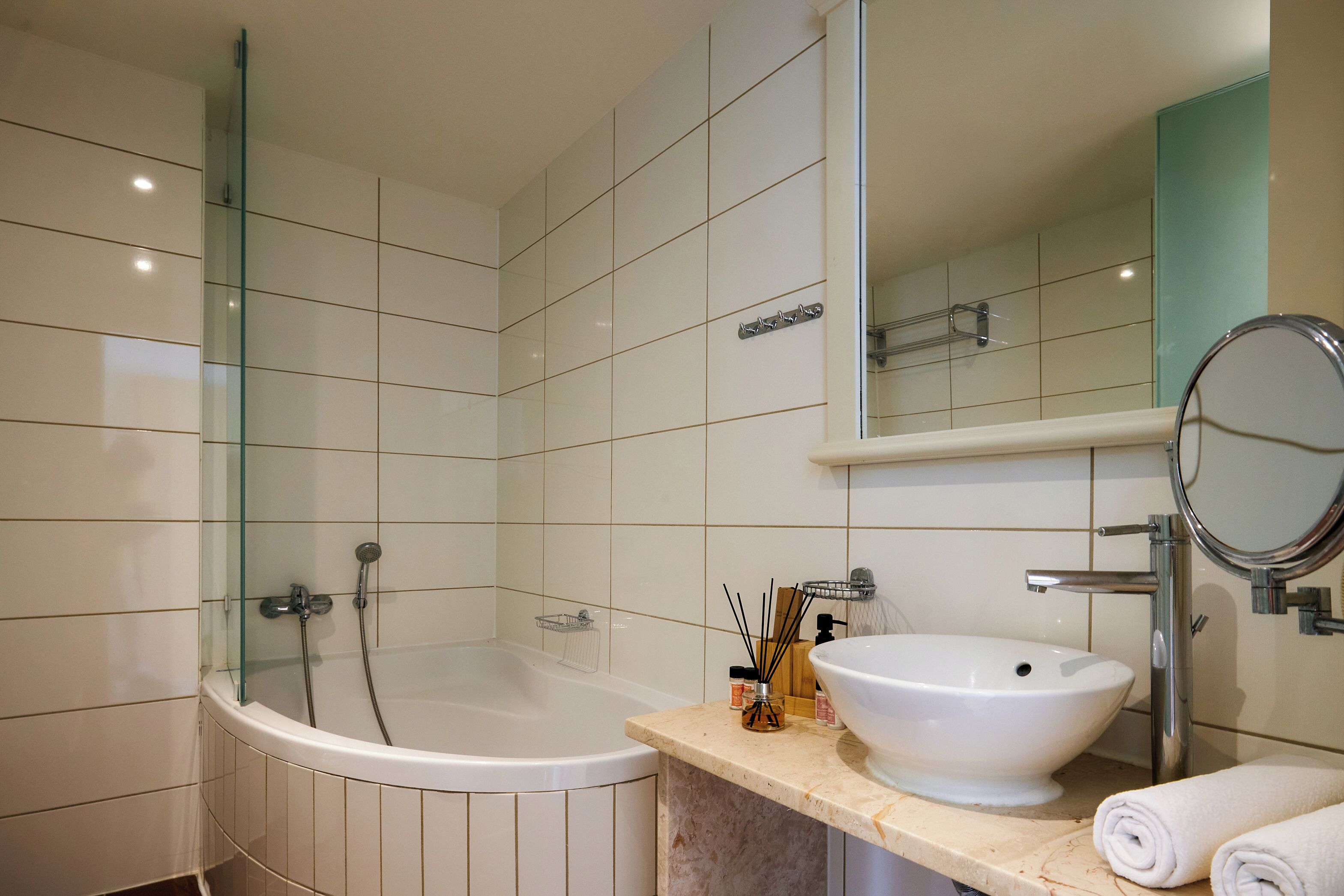 Ein modernes Badezimmer mit einer gläsernen Duschkabine, einer freistehenden Badewanne, einem Waschbecken mit Spiegel und einem Handtuchhalter.