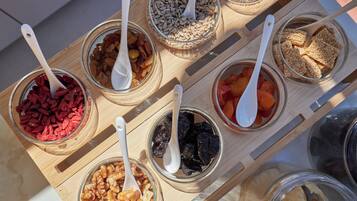 Una bandeja de madera con recipientes de vidrio que contienen diversas frutas secas y nueces.