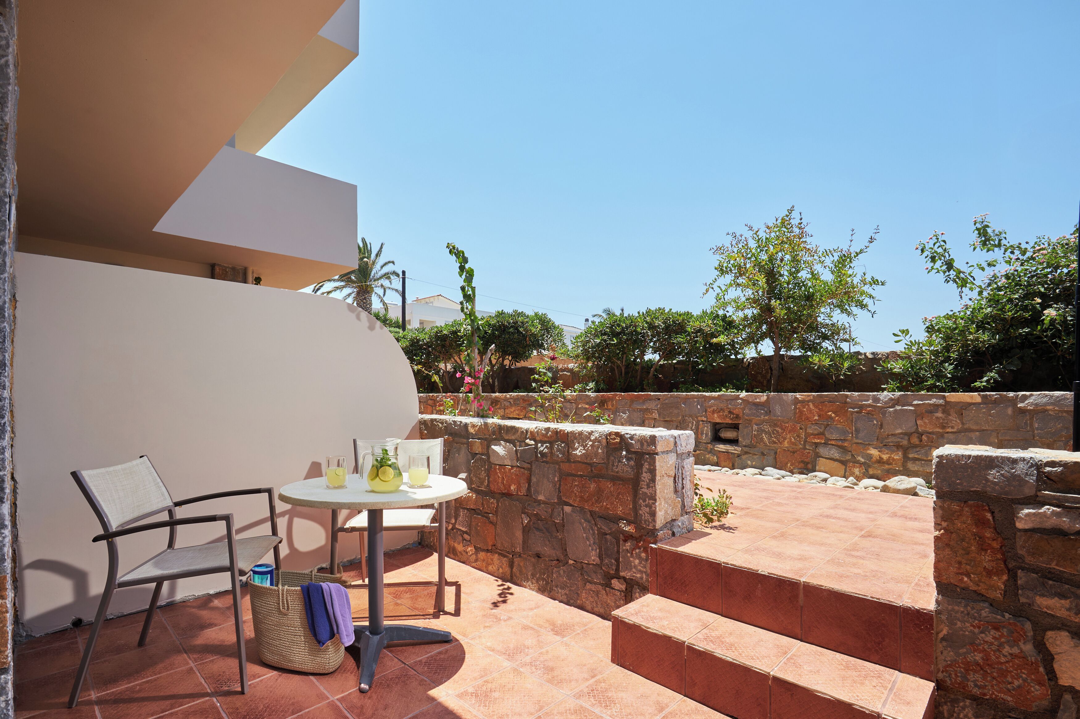 A patio with a table, chair, and stone wall.