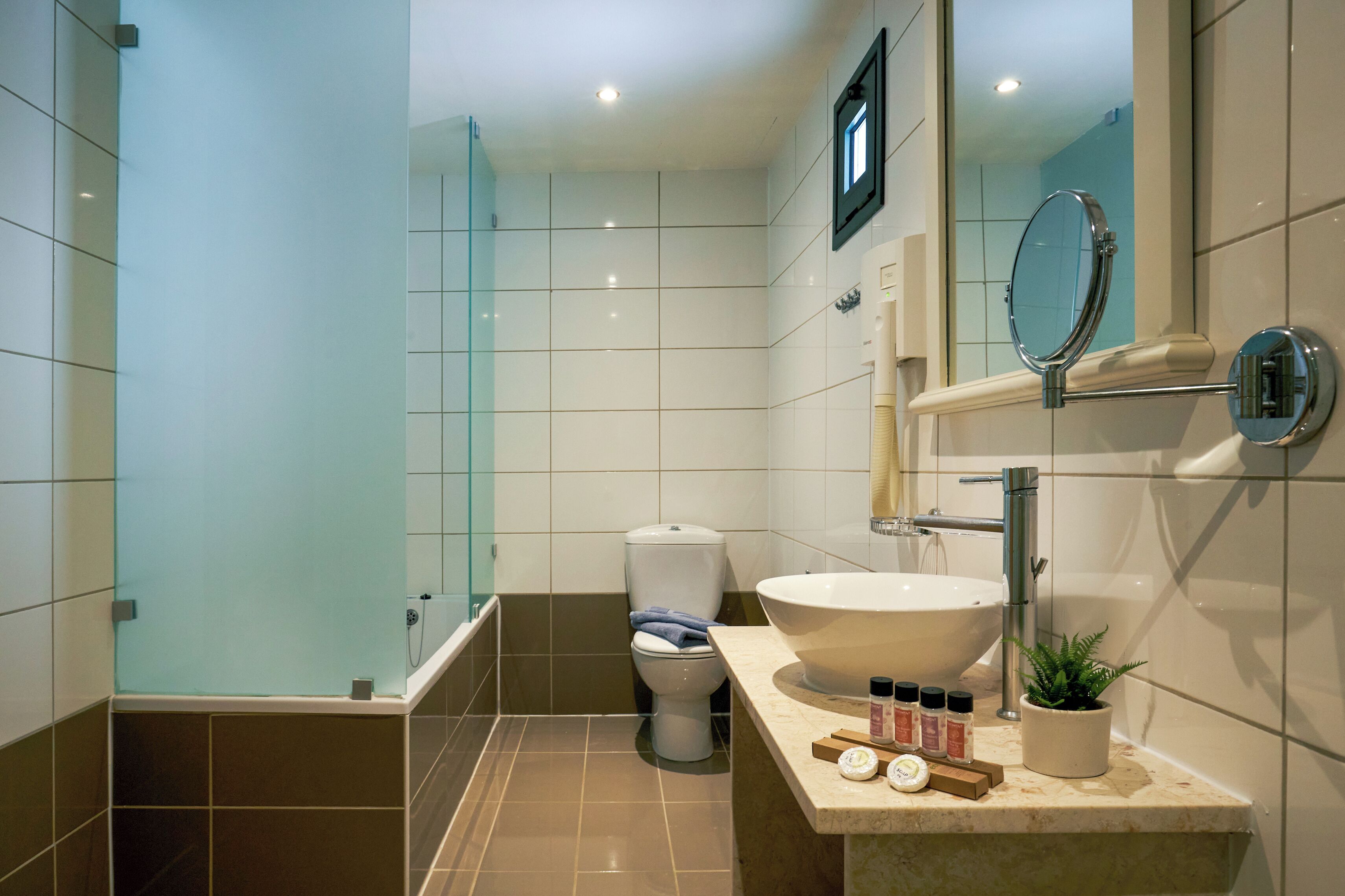 Un baño moderno con cabina de ducha de vidrio, un lavamanos blanco y un espejo.