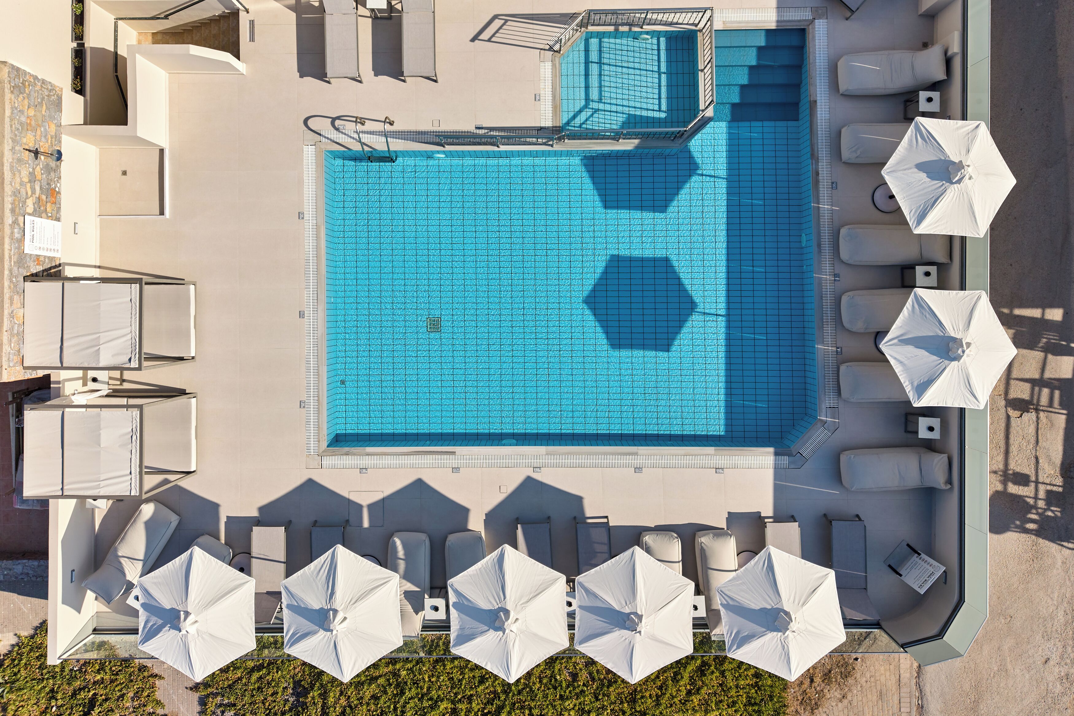 Vista aèria d'una zona de piscina amb gandules i ombrelles.