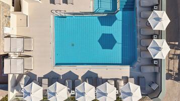 Vista aèria d'una zona de piscina amb gandules i ombrelles.