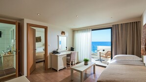 Ett hotellrum med ett skrivbord, en stol, en säng och utsikt över havet.