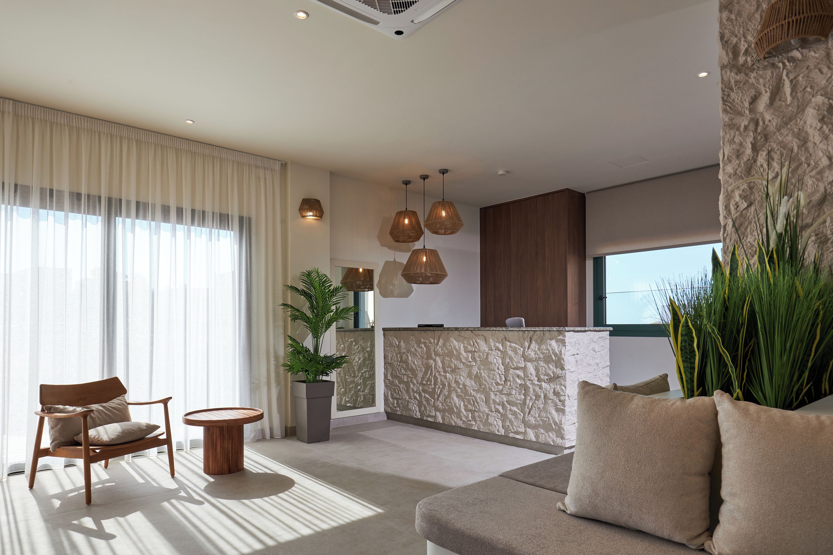 Una sala de estar moderna con un sofá, una silla, una mesa redonda y una recepción con una pared de piedra.