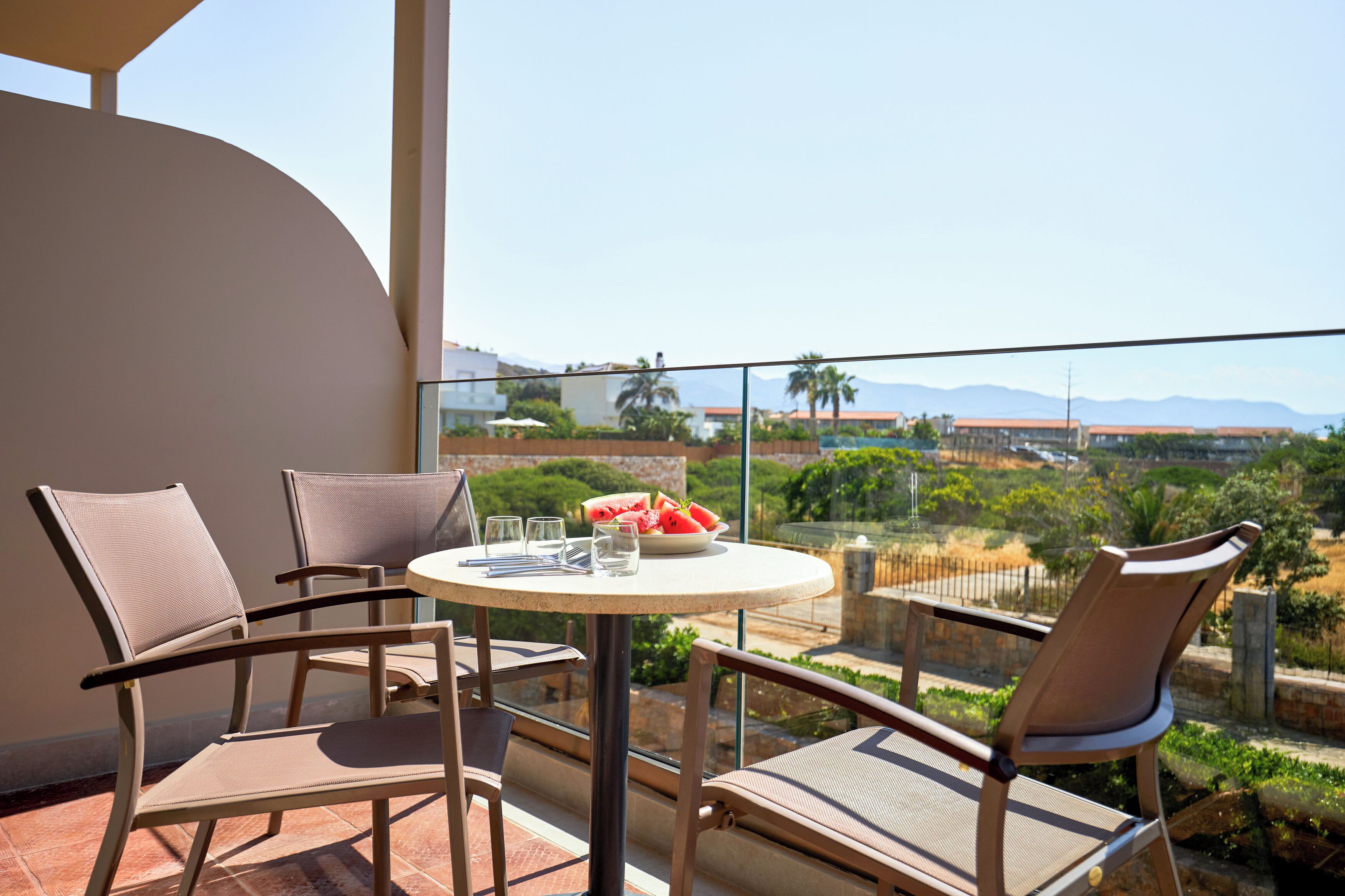 A balcony with a round table, two chairs, and a bowl of fruit.
