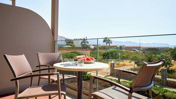 A balcony with a round table, two chairs, and a bowl of fruit.