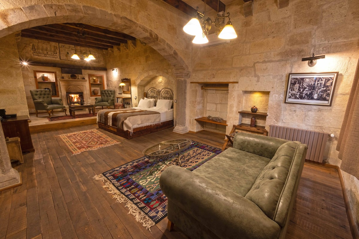 Una habitación rústica con chimenea, dos sillones verdes, una cama y un sofá grande de color verde.