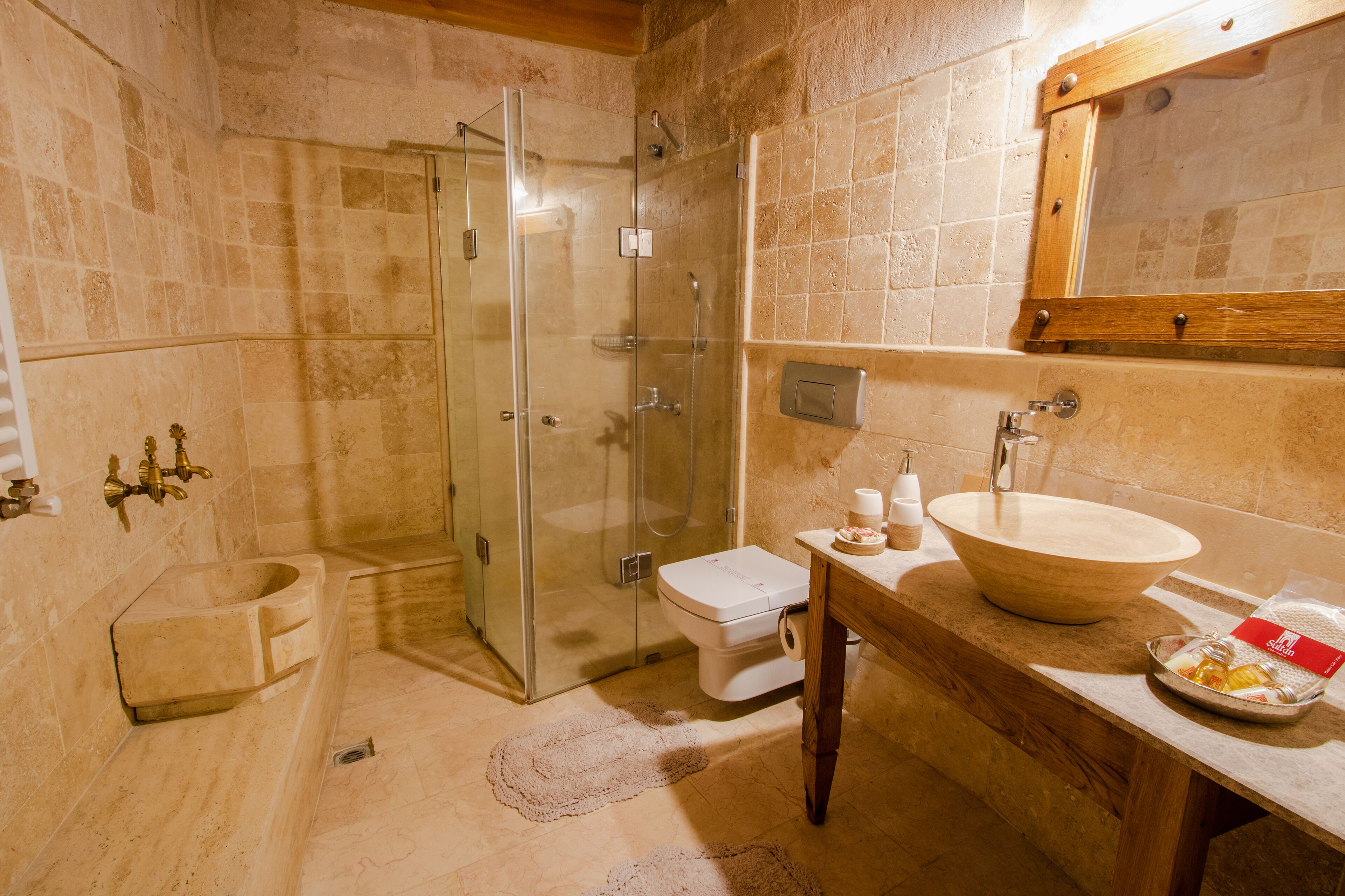 A bathroom with a glass-enclosed shower, a wooden vanity with a large sink, and a toilet.