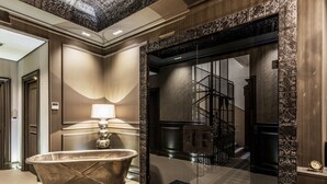 A luxurious bathroom with a freestanding bathtub, a glass-enclosed shower area, and a modern staircase visible through the glass. - Forvm boutique Hotel (Trieste)