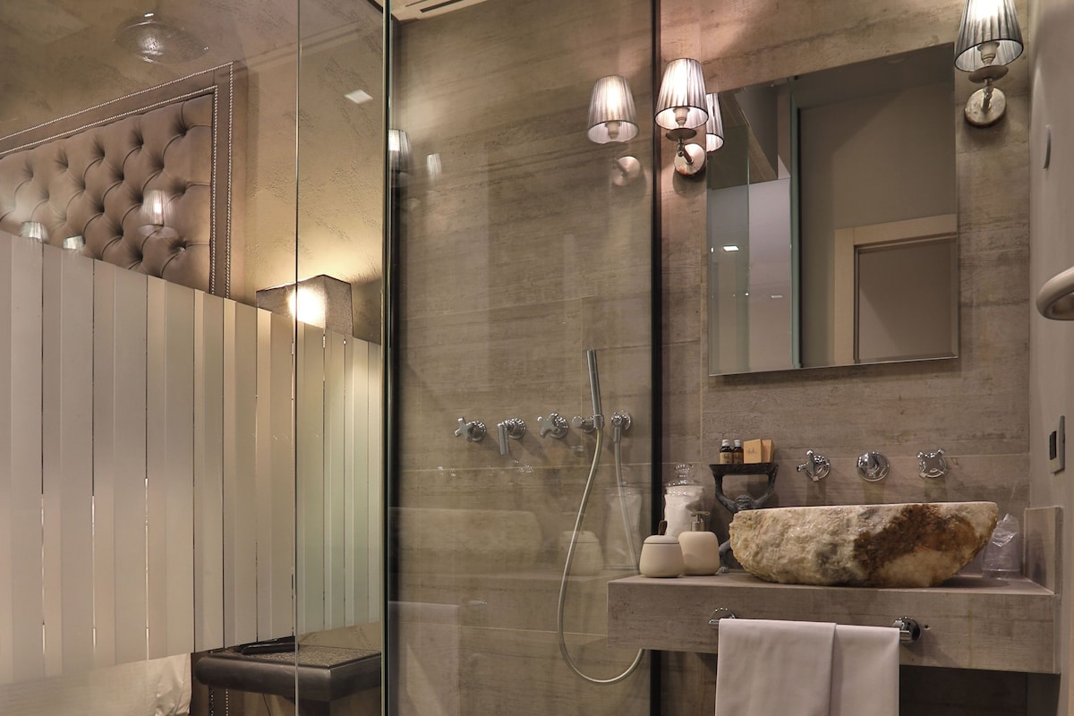 A modern bathroom with a glass-enclosed shower, a large mirror, and a built-in sink.