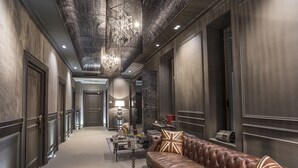 A luxurious hallway with a leather sofa, a chandelier, and a patterned wall. - Forvm boutique Hotel (Trieste)