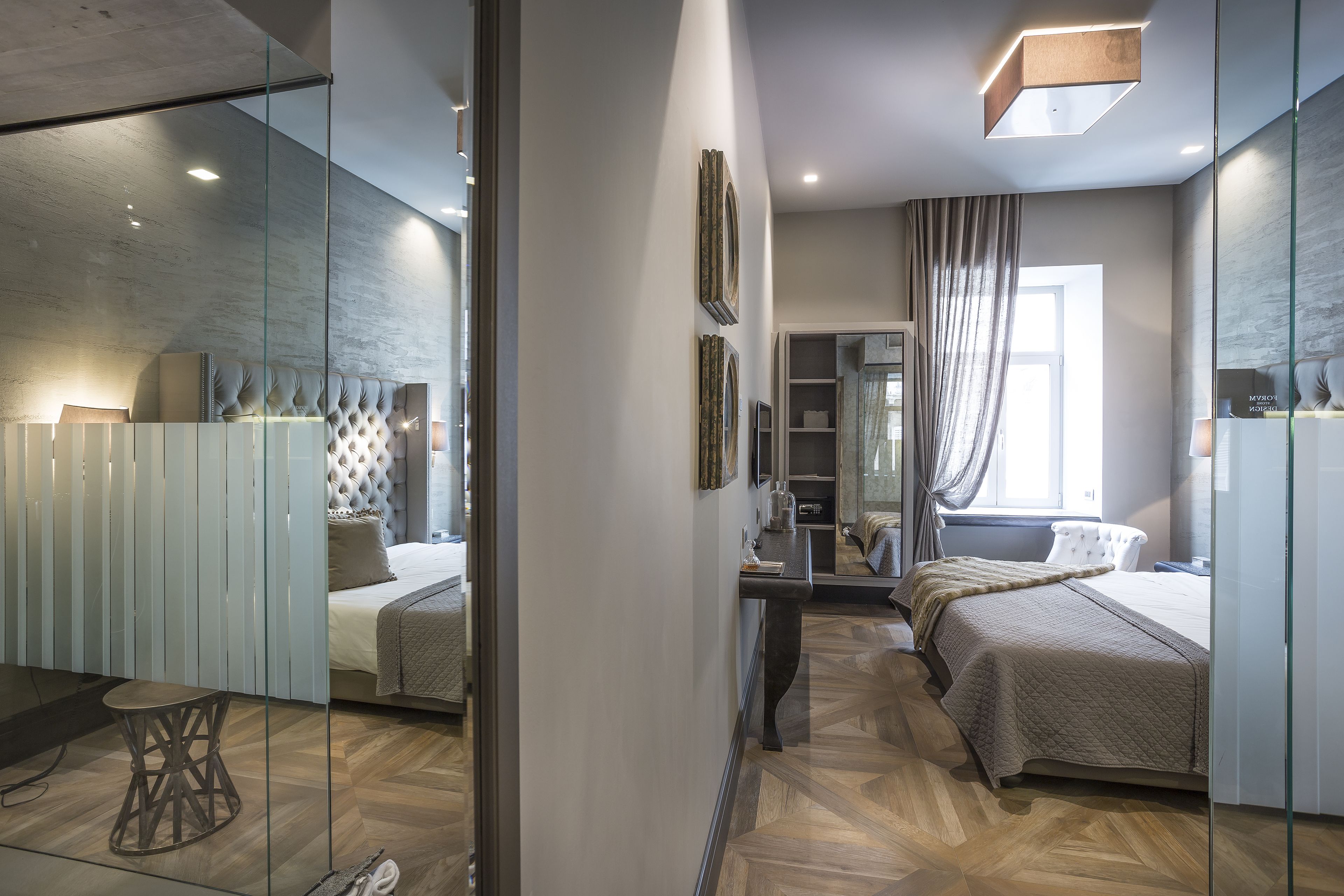 Ein modernes Schlafzimmer mit einem großen Bett, einem kleineren Bett, einem Schminktisch und einer Glaskabine.