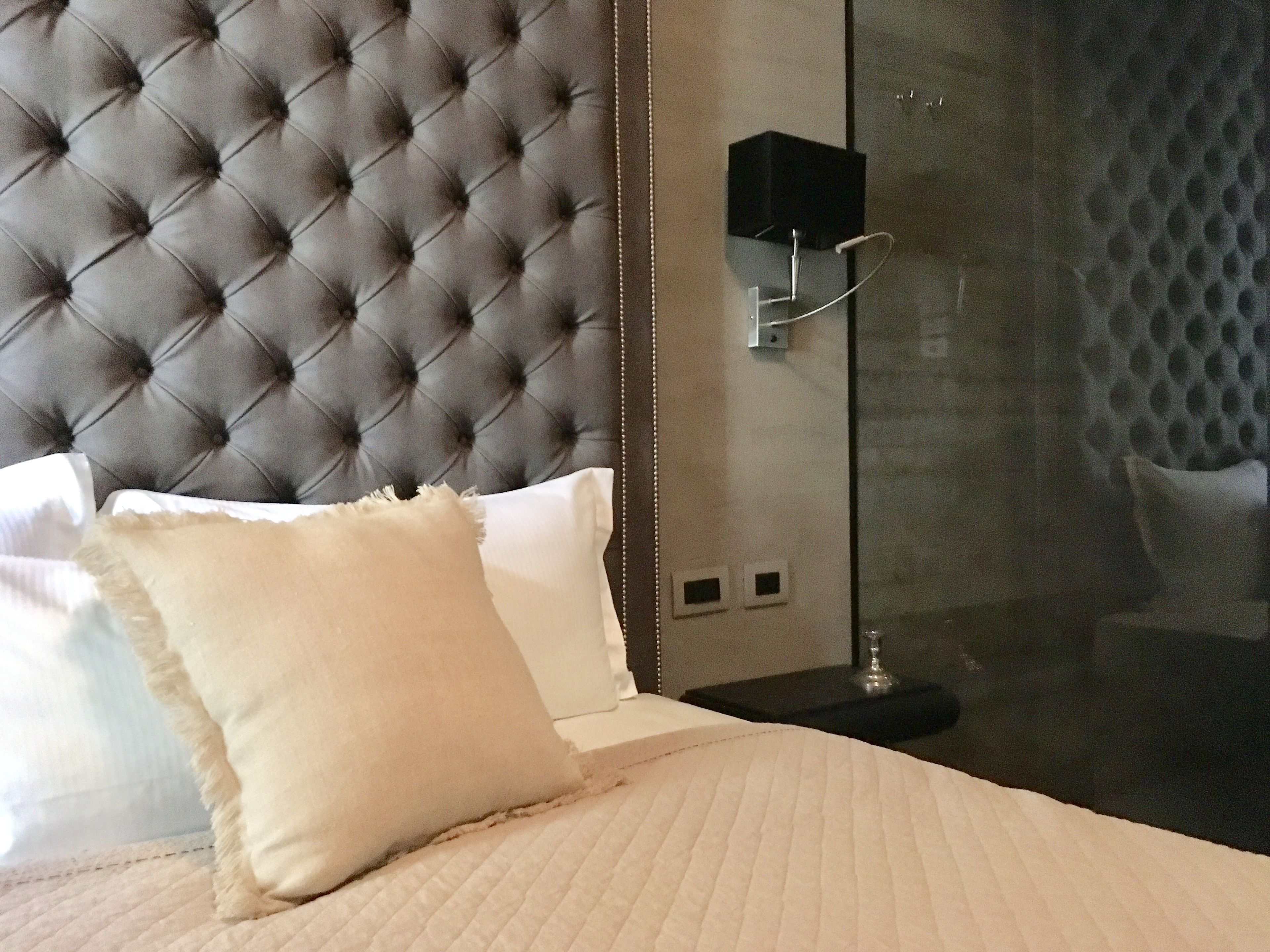 A bed with a tufted headboard, white pillows, and a quilted bedspread.