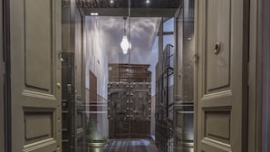 A hotel entrance with a checkered floor, a glass door, and a metal gate. - Forvm boutique Hotel (Trieste)