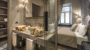 A modern bathroom with a large mirror, a double sink with a unique stone basin, and a glass shower enclosure. - Forvm boutique Hotel (Trieste)