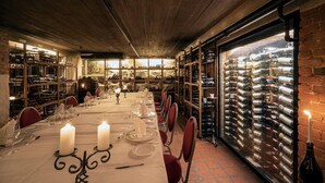 Un espace repas avec une longue table dressée pour le repas, entouré d’étagères à vin et d’une grande cave à vin.