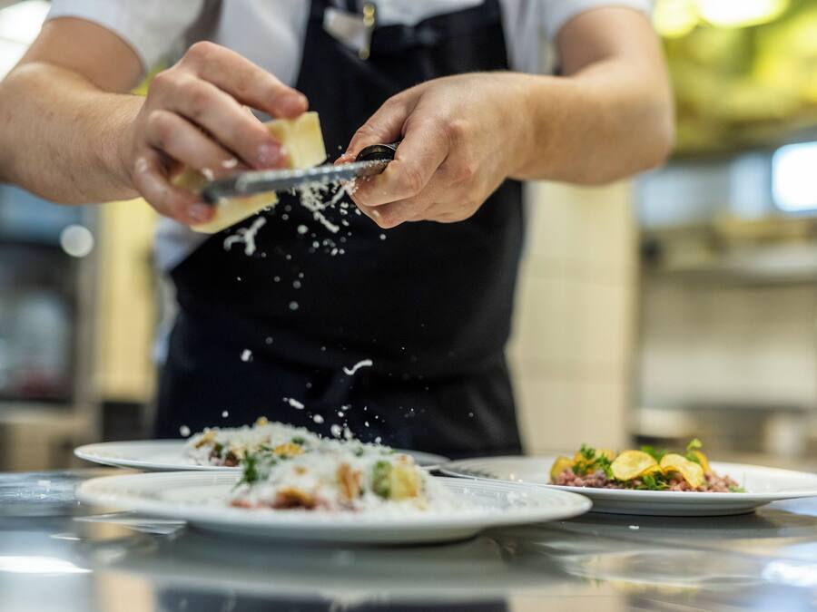 A person grating cheese over a dish.