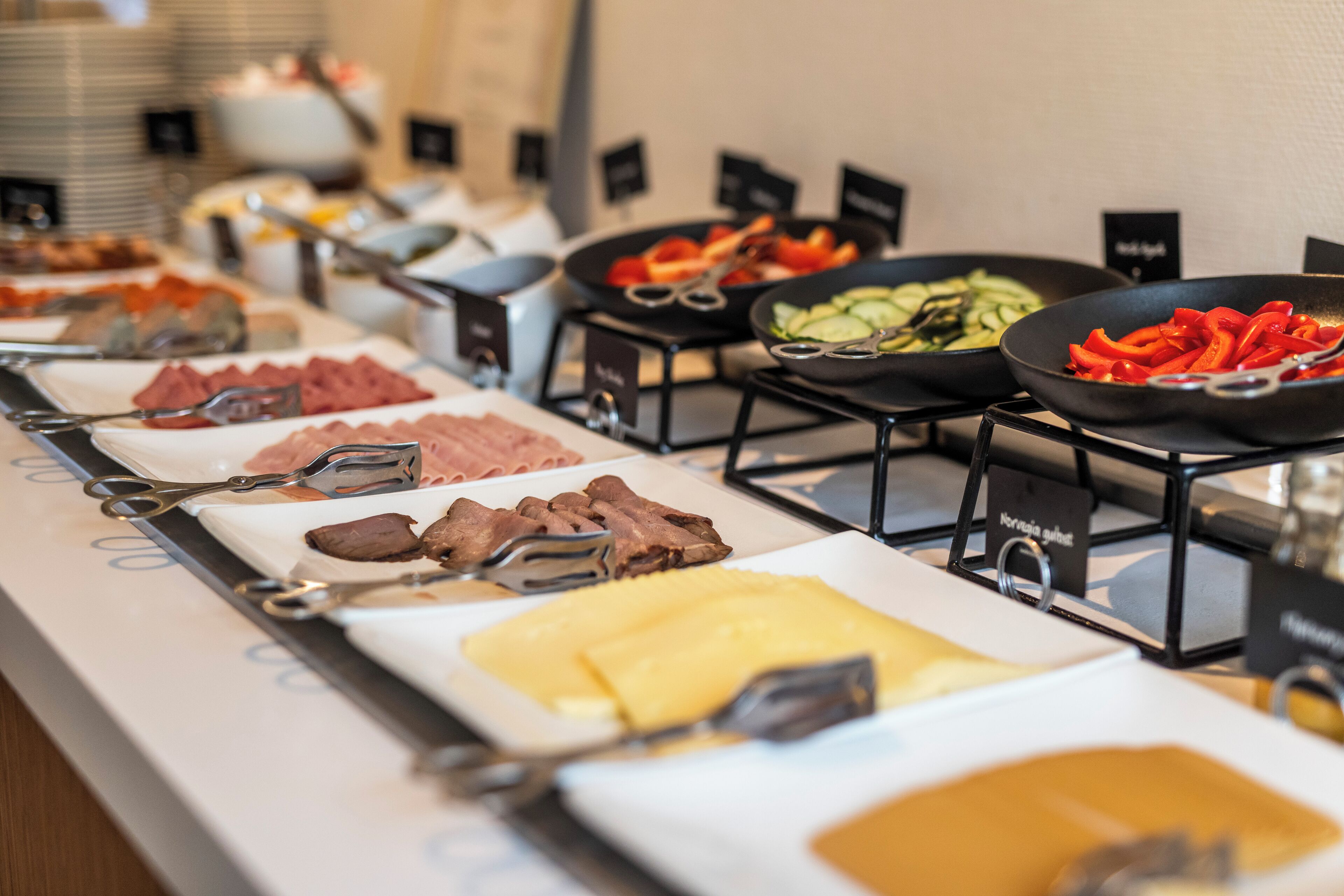 Un bufé con diversas opciones de comida, incluyendo carnes, quesos y verduras.