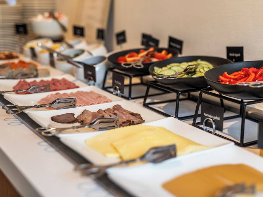 Un bufé con diversas opciones de comida, incluyendo carnes, quesos y verduras.