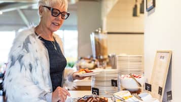 Un buffet proposant une variété de plats et une personne chargée de servir les aliments.