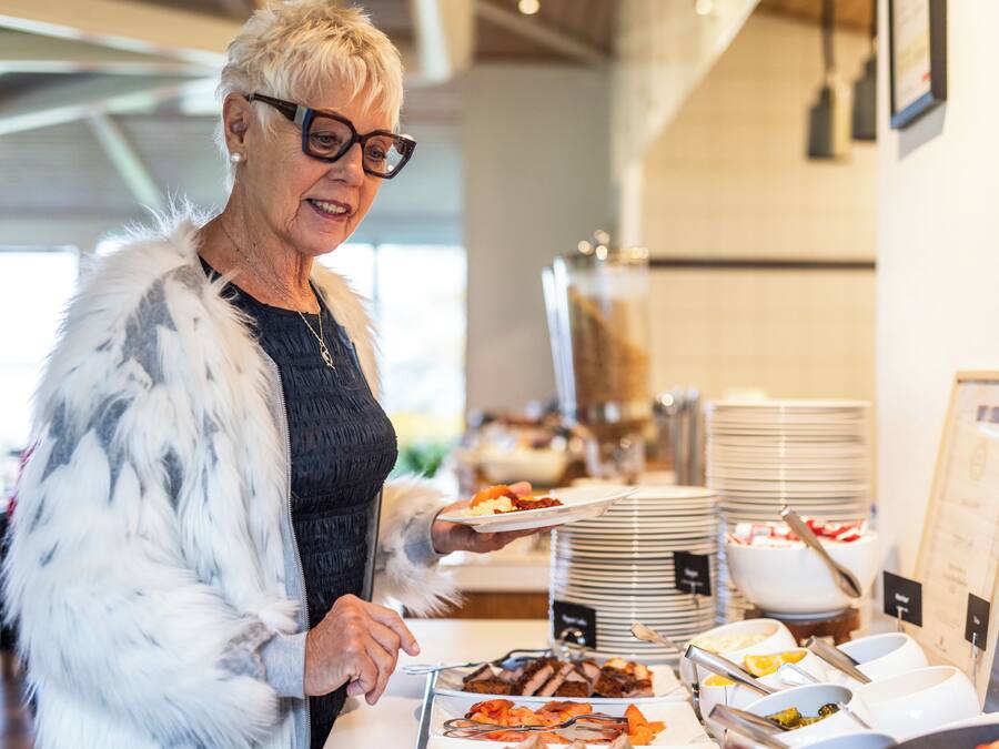 Un buffet proposant une variété de plats et une personne chargée de servir les aliments.
