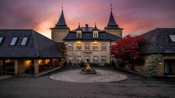 Un bâtiment historique doté d’une cour intérieure, d’une fontaine et d’une façade bien éclairée.